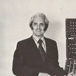 Robert Moog standing beside his modular synthesisers, around 1974